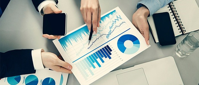 Two people going through printed charts on a desk